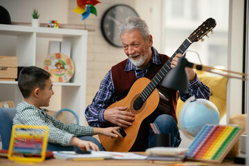Grandpa and grandson playing guitar. Grandfather and grandson enjoying at home.	