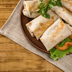 Hot pita bread wrapped with cheese and vegetables and greens on a rustic plate.