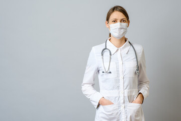 Happy doctor wearing surgical mask isolated on gray