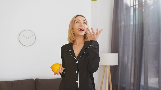 Girl in black pajamas with apple and lemon in her hands.