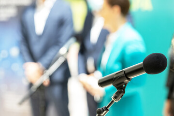 Microphone in focus against blurred people at news conference or press briefing