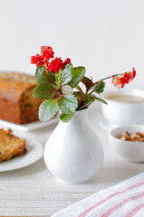 Still life with a small vase with wild flowers and food on a rustic table
