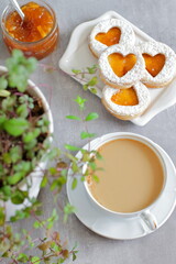 Sweet homemade love sandwich cookies with orange jam and coffee latte