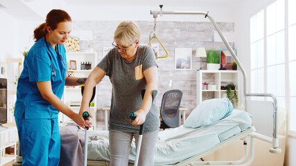 Nurse in retirement home helping an elderly woman to recover her muscle strength. Physiotherapy and...