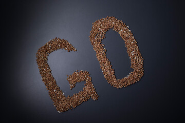 Word 'GO' written with buckwheat On gray background, top view, copy space. Food supplies crisis, food donation on quarantine isolation period.