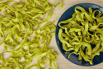 Raw green pasta with spinach on a dark blue plate, top view