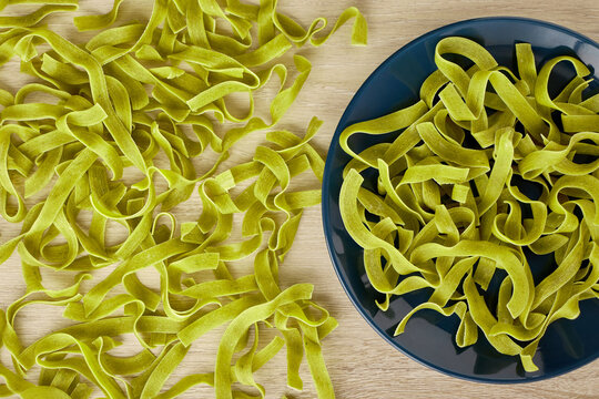 Raw green pasta with spinach on a dark blue plate, top view