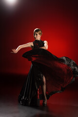 attractive flamenco dancer touching dress while dancing on red