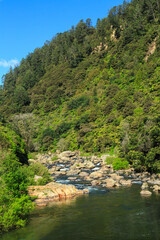 Fototapeta na wymiar A rocky river cascades out of forested mountains. Ohinemuri River in the Karangahake Gorge, New Zealand