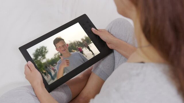 Mother and son communicate through video chat on tablet. Self-isolation, quarantine, pandemic concept.