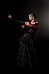 elegant woman gesturing and dancing flamenco on black