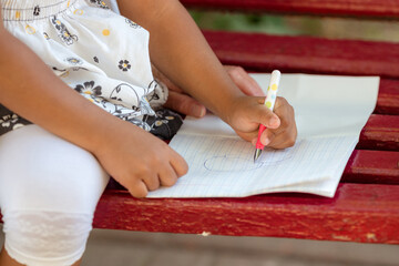 little girl with her grandmother drawing using crayons outdoors.