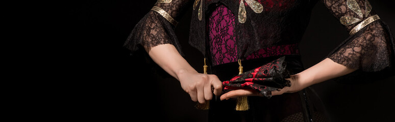 horizontal image of young flamenco dancer holding fan isolated on black