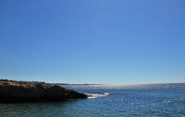 A coastal cliff in a blue sea falling into a blue sky