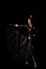 beautiful dancer touching dress while dancing flamenco isolated on black