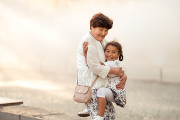 Fototapeta premium Summer portrait of happy grandmother with granddaughter outdoors.