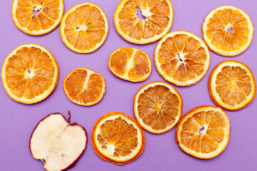 One slice apple stand out between many slices of orange isolated on purple background