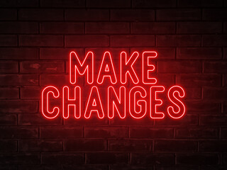 Fototapeta na wymiar Make changes - red neon light word on brick wall background