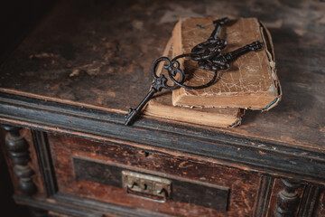 old vintage keys on an old battered book, wooden background.