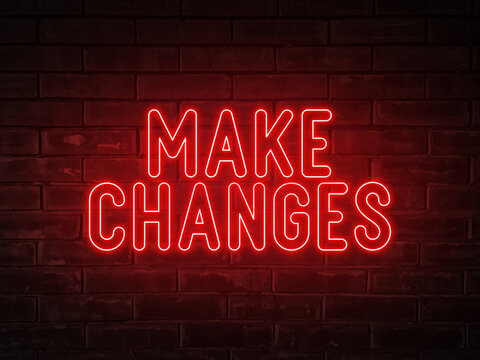 Make changes - red neon light word on brick wall background