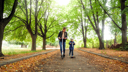 Beautiful young mother teaching her little son riding kick scooter at autumn park © Kyrylo Ryzhov