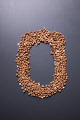 Obraz premium Letter 'o' written with buckwheat On gray background, top view, copy space. Food supplies crisis, food donation on quarantine isolation period