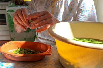 Hands of a senior woman stringing green beans