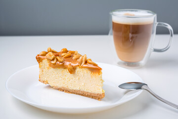 Latte coffee with a piece of cheesecake with caramel and peanuts coating