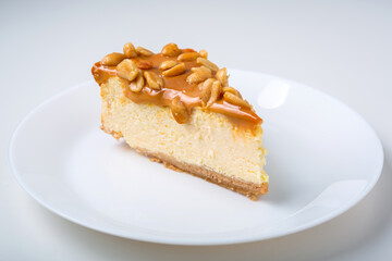 Piece of cheesecake with caramel and peanuts coating