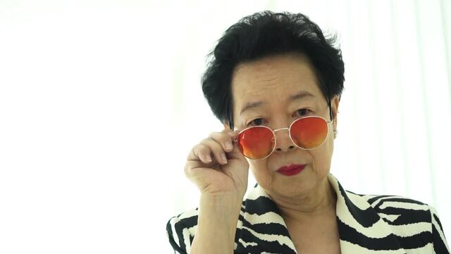 Asian elderly woman with stylish fashion dress colourful sunglasses and zebra pattern dress