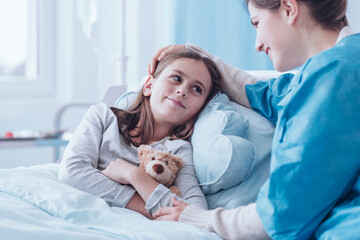 Smiling mother visiting sick daughter in hospital