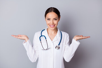 Photo of attractive family doc professional hold two open palms empty space advising good quality vitamins pick select one wear medical uniform lab coat stethoscope isolated grey background