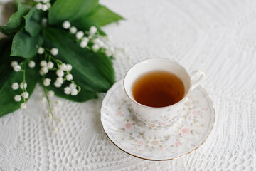 lilies of the valley in the basket and a cup of tea