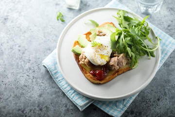 Poached egg with tuna and arugula on toast