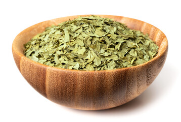 dried parsley flakes in the wooden bowl, isolated on white background