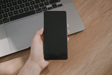 Woman using smartphone in the office by her laptop