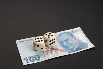 Money, finance and gambling concept: Below of frame 100 (hundred) Turkish TL, lira banknote with Mustafa Kemal Atatürk portrait. Two white dices showing 5 and 6. Dark background and space for text