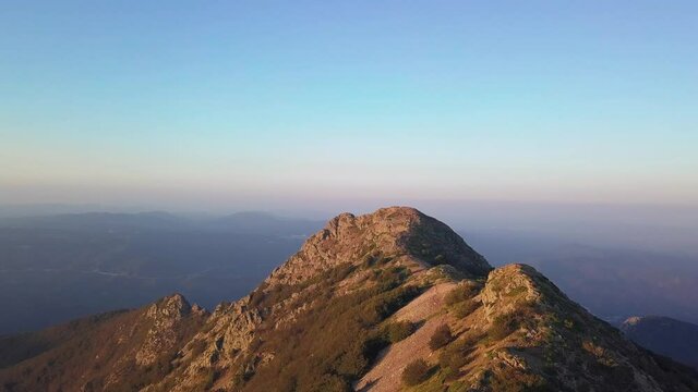 Aerial drone shot approaching a rocky mountain peak named "Les Agudes" during sunset. Montseny, Barcelona, Spain.