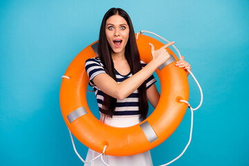 Photo of excited lady long hair hold orange emergency life buoy directing finger empty space...