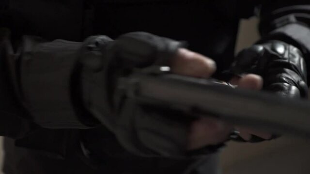 Hands in black military gloves jerks the bolt and charges the gun