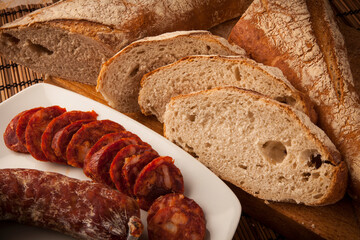 rebanadas pan masamadre con decoración de chorizo en plato sobre fondo de madera