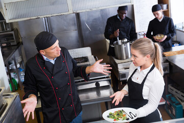 Bewildered chef talking with waitress