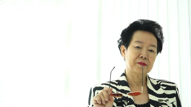 Confident Asian elderly woman with stylish fashion dress colourful sunglasses and zebra pattern dress