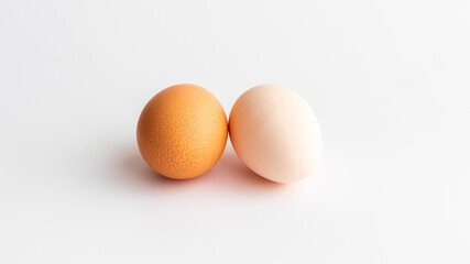 One is brown and the other is white, two eggs on the white background 