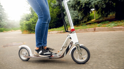 Closeup iamge of female feet riding on kick scooter at park