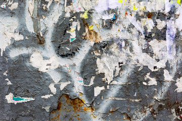 Creative background of rusty metal, painted gray paint carelessly with the remnants of torn paper....