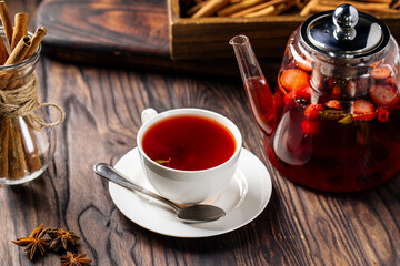 Hot sweet berry tea in white cup and glass teapot