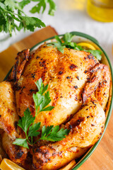 Whole roasted chicken with fresh parsley and lemon wedges in a festive dish