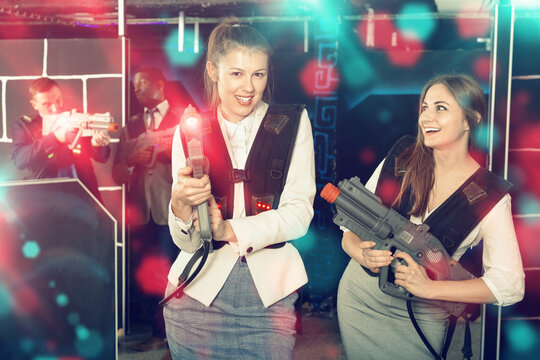 Portrait Of Two Women In Business Suits Playing Laser Tag With C