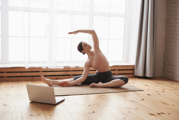 Young attractive woman practicing yoga online